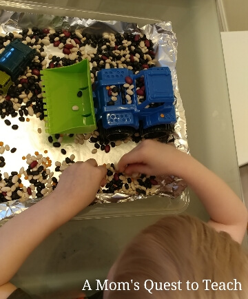 child playing with toy truck and beans