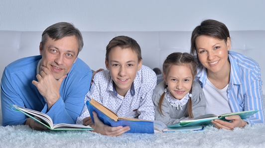 Family all reading books together.  Mom, Dad, Son and Daughter each holding a book.